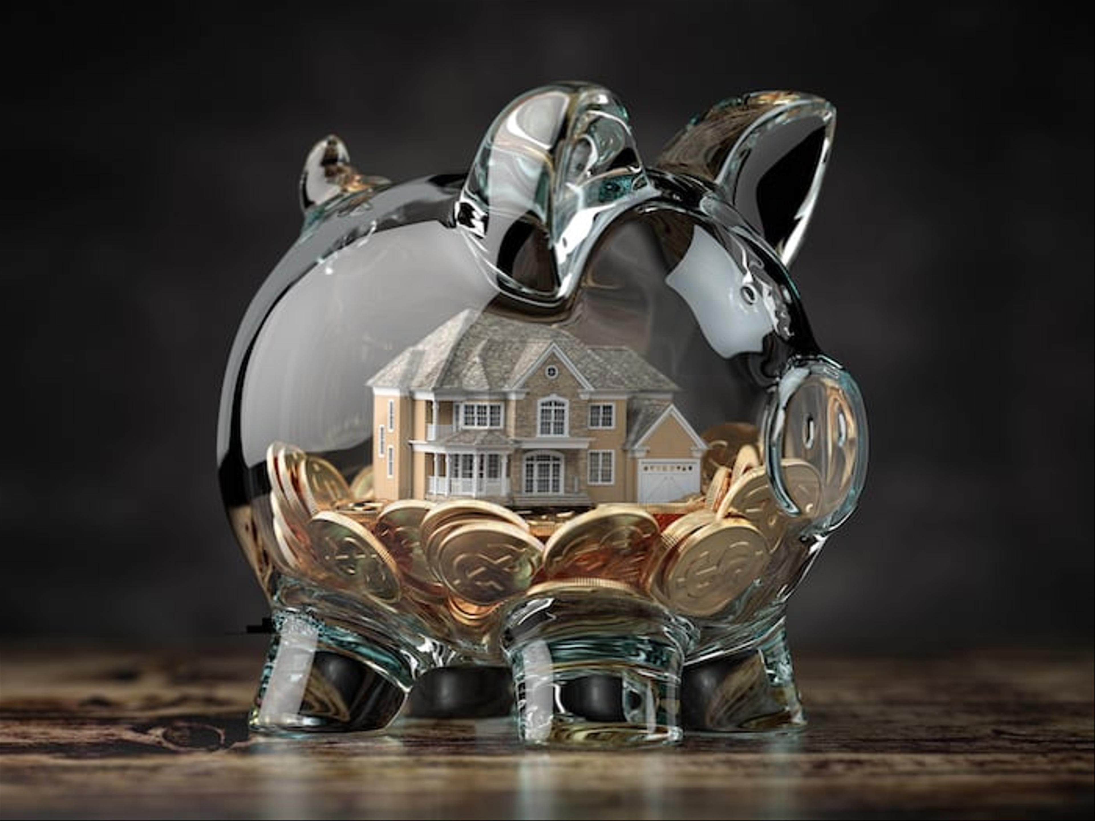 Glass piggy bank with coins and a house inside of it