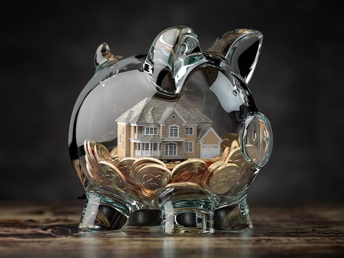 Glass piggy bank with coins and a house inside of it